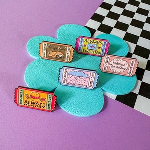 May include: Set of six enamel pins featuring colourful ticket designs with humorous phrases like "Always Tired", "Always Exhausted", "Always Anxious", "Always Overthinking", "Always Hungry".
