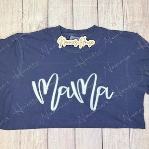 May include: A navy blue t-shirt with the word "Mama" written in white cursive lettering.