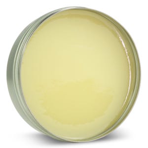 Puede incluir: Un recipiente redondo de hojalata lleno de un b&aacute;lsamo o ung&uuml;ento de color amarillo p&aacute;lido.