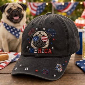 May include: A charcoal gray baseball cap featuring an embroidered pug wearing American flag sunglasses, surrounded by fireworks and stars. The text 'MERICA is embroidered in red, white, and blue. A small pug graphic and paw print are on the brim.