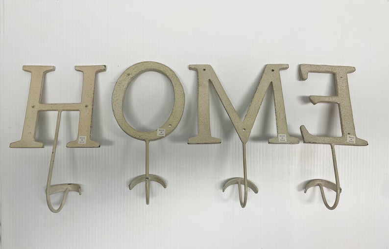 Puede incluir: Letrero HOME de metal blanco con ganchos. Cada letra es un gancho separado.
