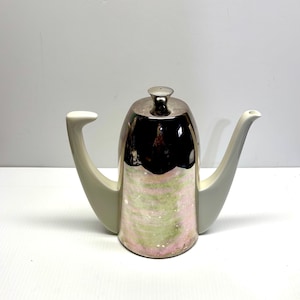 May include: A decorative teapot with a silver lid and a pearlescent body featuring pink and green swirls. The teapot has a white handle and spout. This unique teapot is a stylish addition to any kitchen.