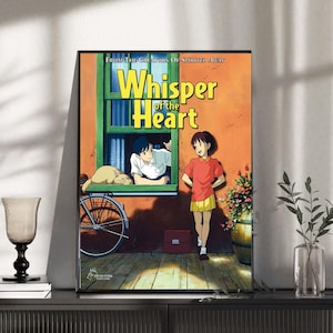 May include: A framed poster featuring the anime film "Whisper of the Heart." The artwork depicts two characters, a boy and a girl, with a cat, a bicycle, and the film's title in yellow. The background is a warm orange and green.