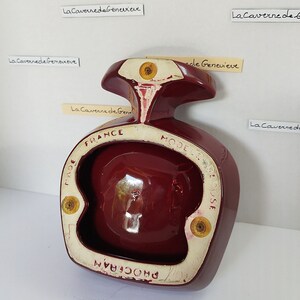 May include: A burgundy ceramic ashtray shaped like a bird with a round bowl. The ashtray has the text "FRANCE" and "MODELE DEPOSE" printed on the bottom.