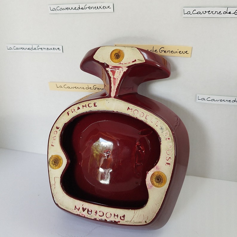 May include: A burgundy ceramic ashtray shaped like a bird with a round bowl. The ashtray has the text "FRANCE" and "MODELE DEPOSE" printed on the bottom.