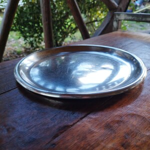 May include: A shiny silver serving tray with a slightly raised rim sits on a wooden table.