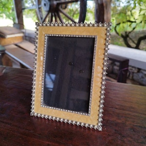 May include: A yellow picture frame with a pearl-like border and a silver trim. The frame is empty and ready for a photo.