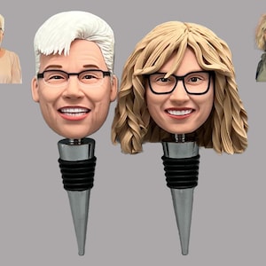 May include: Two personalized wine bottle stoppers featuring realistic faces of two people. The stoppers are silver with black rubber stoppers.