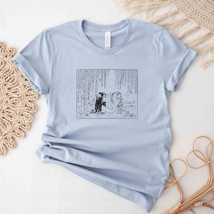 May include: Light blue t-shirt with a black and white illustration of two women in a river with willow trees.