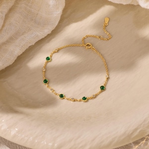 Puede incluir: Una delicada pulsera de cadena dorada con piedras redondas alternas, verdes y transparentes, engastadas en biseles dorados. La pulsera incluye una fina extensi&oacute;n de cadena con una peque&ntilde;a etiqueta dorada en el extremo.