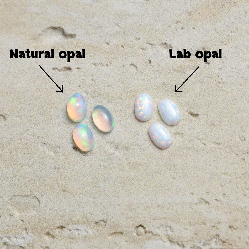 May include: Image showing two groups of oval-shaped opals. The text "Natural opal" points to a group of three opals with iridescent colors. The text "Lab opal" points to a group of three white opals with a subtle sparkle.