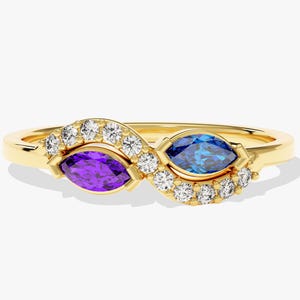 Könnte beinhalten: Ein goldener Ring mit einem Marquise-geschliffenen Amethyst und einem Marquise-geschliffenen blauen Saphir, beide in einem Halo aus kleinen runden Diamanten gefasst.