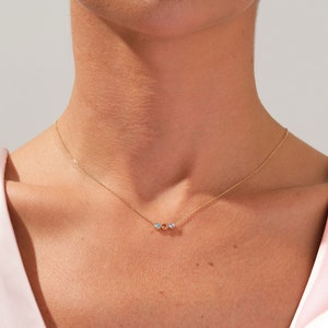 May include: A delicate gold chain necklace with three small iridescent stones.