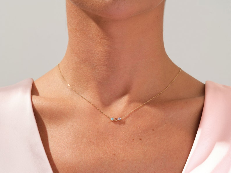 May include: A delicate gold chain necklace with three small iridescent stones.