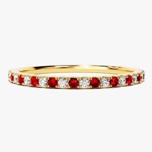 May include: A gold band ring with a row of alternating red and white gemstones.