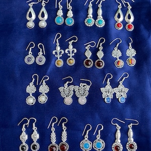 May include: A collection of 18 pairs of silver dangle earrings with various coloured stones and designs. The earrings feature a variety of styles, including floral, butterfly, and geometric designs.