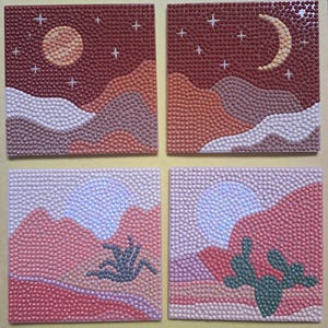 May include: Four square art pieces depicting desert landscapes with a dot art technique. Each piece features a different scene: a moon and stars, a crescent moon and stars, and two with a sun and cacti. The color palette includes shades of pink, brown, and white.
