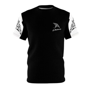 May include: A black short-sleeved t-shirt with white sleeves featuring black tribal-style patterns. The chest area displays a white graphic of a manta ray above the text El Mantarraya in a script font, positioned on the upper right side.