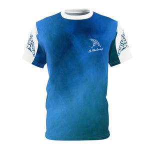 May include: A short-sleeve t-shirt featuring a blue gradient background with a white manta ray graphic and the text El Mantarraya on the chest. The sleeves are white with intricate blue tribal-style patterns on the outer edges and a crew neckline.