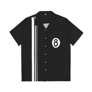 Peut inclure: Une chemise boutonnée à manches courtes noire avec des rayures blanches sur le côté et un cercle blanc avec le chiffre "8" au centre sur la poche poitrine gauche.