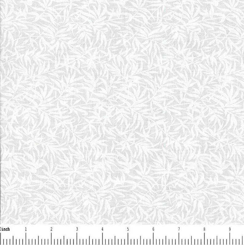 May include: A white fabric featuring a repeating pattern of light gray leaves and stems. A ruler is visible at the bottom edge, showing a scale in inches from 0 to 9, indicating the fabric texture and the density of the botanical print design.