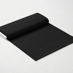 May include: A black fabric swatch, folded in half, with a smooth texture.