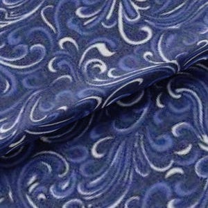 May include: Close-up of a fabric with a swirling pattern in shades of blue and white. The design features flowing, organic shapes reminiscent of waves or stylized floral elements. The fabric appears to have a soft texture.