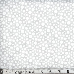 May include: A light gray fabric featuring a pattern of white polka dots of varying sizes. A Dritz measuring tape is positioned along the bottom edge, showing a length of 8 inches with clear black markings on a white background for scale.
