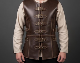 May include: A brown leather vest with multiple brass buckles. The vest has a round neckline and is worn over a long-sleeved beige shirt. The vest features decorative stitching and a tailored fit, suggesting a medieval or Renaissance theme.