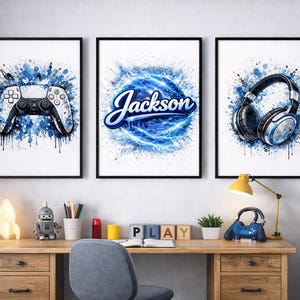 May include: Three framed art prints with gaming themes. One shows a white and black game controller, another displays the name "Jackson" in blue script, and the third depicts headphones. All are set against blue watercolour splashes.