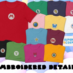 May include: A collection of 11 t-shirts featuring embroidered video game character logos. The logos include Mario, Luigi, Donkey Kong, Wario, Peach, Yoshi, Toad, and more. The shirts are all different colors, including red, green, blue, yellow, pink, and black. The text "SUPER-STAR COSPLAY" is visible in the top right corner of the image. The text "EMBROIDERED DETAIL!" is visible at the bottom of the image.