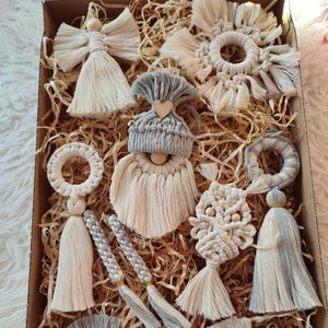 May include: A set of nine handmade macrame ornaments in a variety of shapes and colours, including a gnome, angel, and star. The ornaments are made with natural cotton cord and feature a variety of textures and patterns. They are perfect for adding a touch of bohemian charm to your home decor.