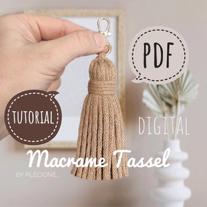 May include: A beige macrame tassel keychain with a silver clasp. The image includes the text "Tutorial", "PDF", "Digital", and "Macrame Tassel". The keychain is held in a hand against a neutral background.