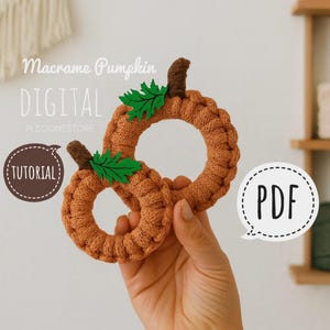 Peut inclure: Deux citrouilles en macramé faites à la main, de couleur orange, avec des tiges marron et des accents de feuilles vertes. Les citrouilles sont circulaires et comportent le texte "Macrame Pumpkin DIGITAL", "TUTORIAL" et "PDF".
