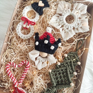 May include: A set of five handmade Christmas ornaments in a box. The ornaments are made of yarn and include a snowman, a gnome, a candy cane, a snowflake, and a Christmas tree.