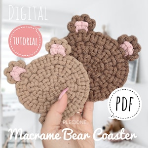 May include: Two brown macrame bear coasters with pink ears. The coasters are held in a hand. The text "DIGITAL TUTORIAL" and "PDF" are in speech bubbles. The text "PLECIONE_ Macrame Bear Coaster" is at the bottom of the image.
