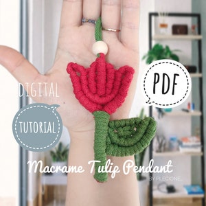 May include: A digital PDF tutorial for making a macrame tulip pendant. The image shows a hand holding the finished pendant, which is red and green. The text "DIGITAL TUTORIAL" and "PDF" are in speech bubbles.