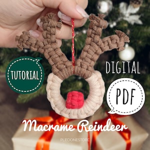 May include: A macrame reindeer ornament with brown antlers and a white and red face. The ornament is hanging from a red string. The text "DIGITAL PDF" and "TUTORIAL" are in speech bubbles on the image. The text "Macrame Reindeer" is below the ornament.