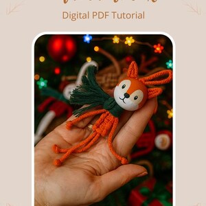Pu&ograve; includere: Ornamento a forma di volpe in macram&egrave; fatto a mano con dettagli arancioni e verdi. La volpe ha un viso bianco con occhi neri e un naso nero. Il testo "Macrame Fox" e "Digital PDF Tutorial" &egrave; visualizzato in alto.