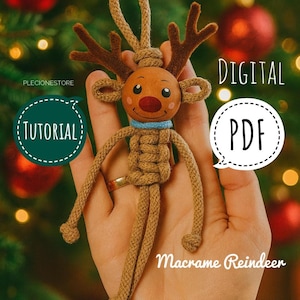 May include: A macrame reindeer decoration made from brown cord, with a round head, antlers, and a blue collar. The image includes the text "DIGITAL PDF" and "TUTORIAL".