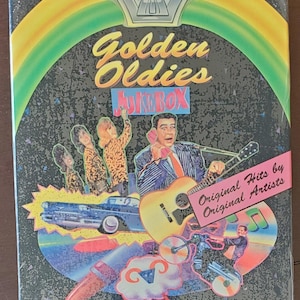 May include: A compact disc case for a music video game called "Golden Oldies Jukebox". The case features a colorful design with a retro theme, including a vintage car, a guitar, and a jukebox. The text "Original Hits by Original Artists" is printed on the case.
