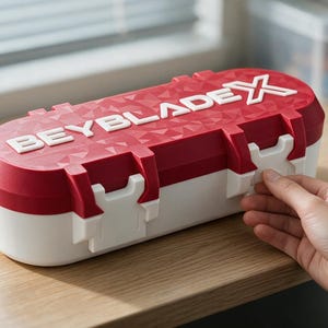 Può includere: Una custodia ovale con coperchio rosso e base bianca. Il coperchio presenta un motivo geometrico testurizzato e la scritta bianca in rilievo BEYBLADE X. La custodia è dotata di due chiusure in plastica bianca sul davanti per fissare il coperchio.