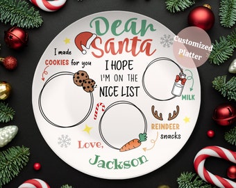 May include: White ceramic plate with a Christmas theme. It says "Dear Santa" and has spaces for cookies, milk, reindeer snacks, and a personalized message. The plate is surrounded by Christmas decorations like ornaments and candy canes.