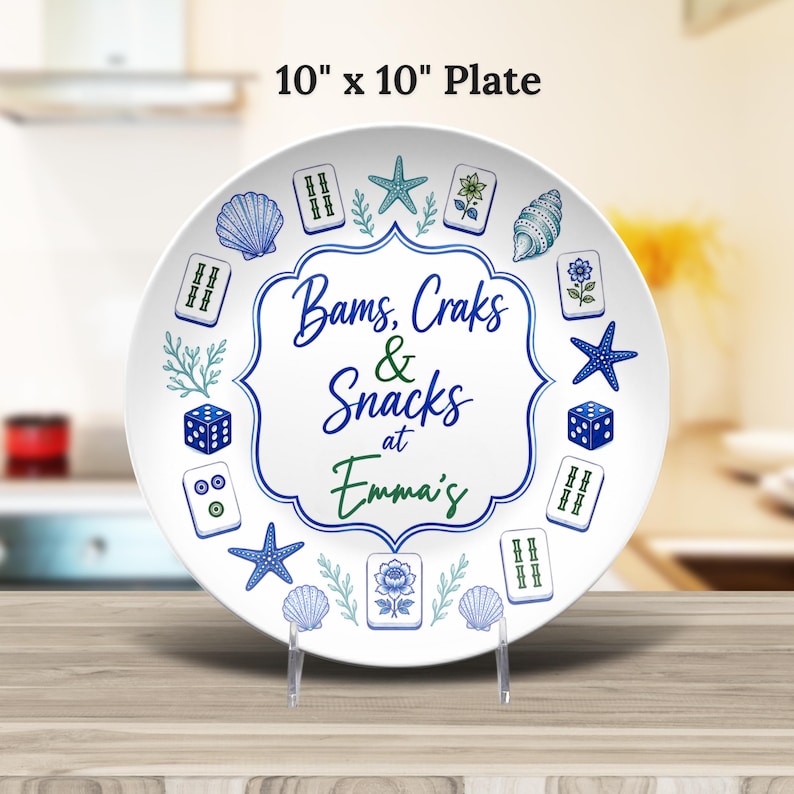 Puede incluir: Un plato redondo blanco de 25,4 cm por 25,4 cm con un borde decorativo azul y verde y el texto Bams, Craks & Snacks at Emma's. El dise&ntilde;o incluye ilustraciones de fichas de mahjong, estrellas de mar azules, conchas marinas y dados.