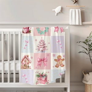May include: A pink and white Christmas themed baby blanket with a patchwork design. The blanket features images of a gingerbread house, a candy cane, a Christmas tree, a bow, a gingerbread man, and a gift box.