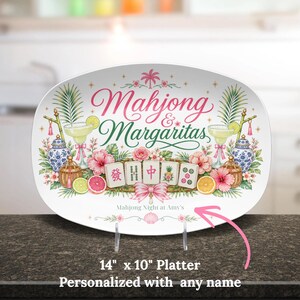 May include: Oval platter with the text "Mahjong & Margaritas" in pink and green. The platter features illustrations of cocktails, flowers, and mahjong tiles. The platter measures 14 inches by 10 inches.