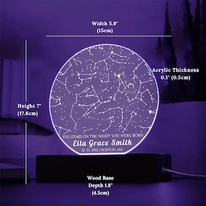 May include: A personalized night light featuring a constellation design. The acrylic display is 5.9 inches (15cm) wide and 7 inches (17.8cm) tall, with a 0.1-inch (0.5cm) thickness. It includes a wooden base with a depth of 1.8 inches (4.5cm). The text reads: "THE STARS ON THE NIGHT YOU WERE BORN Ella Grace Smith 12.12.2012 | BOSTON, MA."