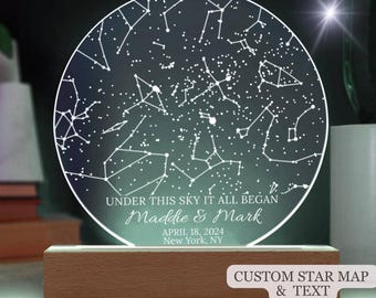 Op de afbeelding: Een gepersonaliseerde sterrenkaart nachtlamp met een houten voet. De kaart toont de sterrenbeelden zoals ze op 18 april 2024 in New York, NY, verschenen. De tekst "UNDER THIS SKY IT ALL BEGAN Maddie & Mark APRIL 18, 2024 New York, NY" is op het licht gedrukt.