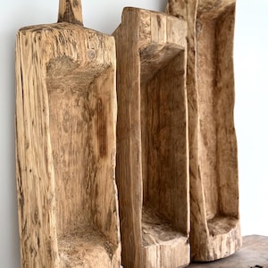 May include: Three rustic, wooden troughs with a natural, weathered appearance. The troughs are rectangular with a hollowed-out interior, and vary in height and width. The wood grain is visible, and the color is a warm, light brown.