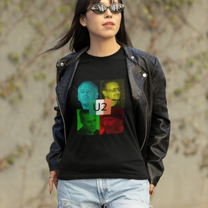 May include: A black short-sleeved t-shirt featuring a graphic print of the band U2. The design includes four individual portraits of the band members arranged in a grid, overlaid with the Irish flag colors and the text U2 in the center.